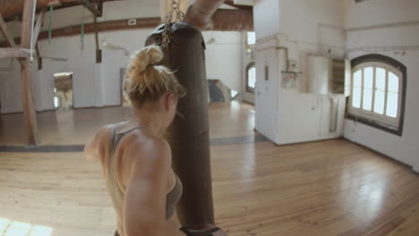Back-view-of-confident-woman-punching-heavy-bag